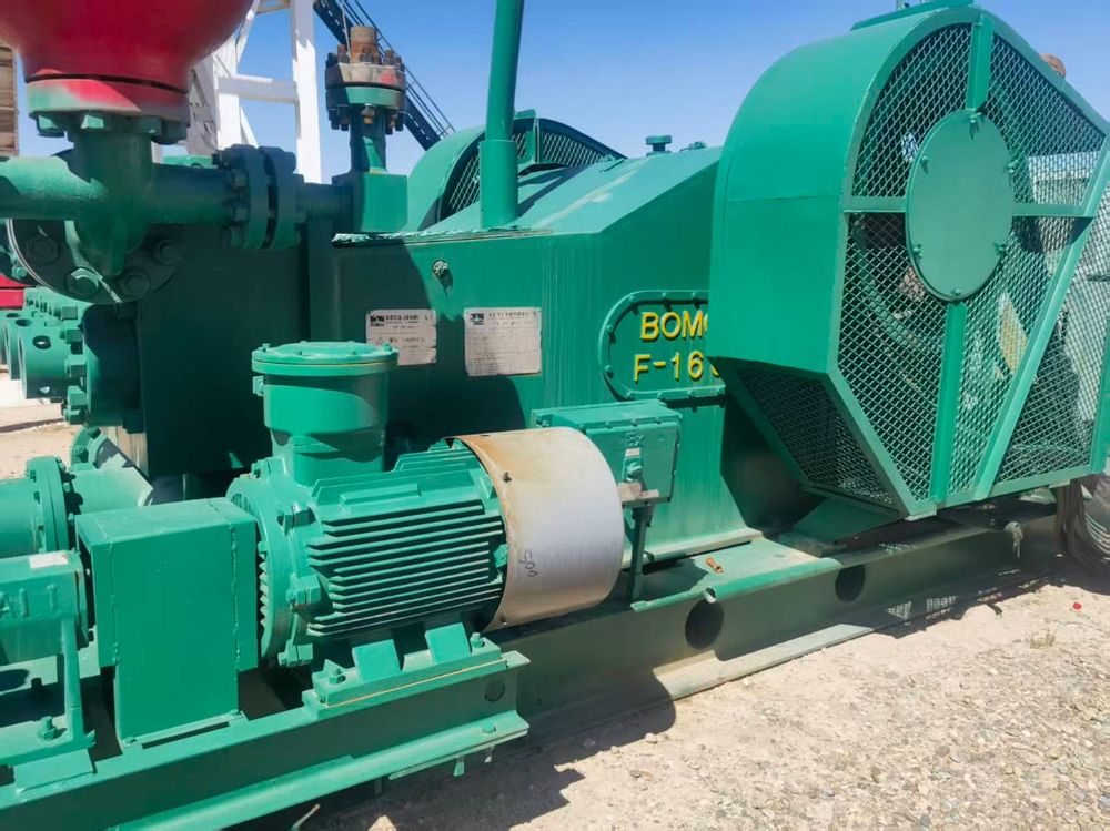 Green skid-mounted triplex mud pump unit on a drilling location